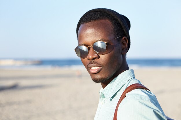 Outdoor shot of fashionable young man in headwear and eyeglasses