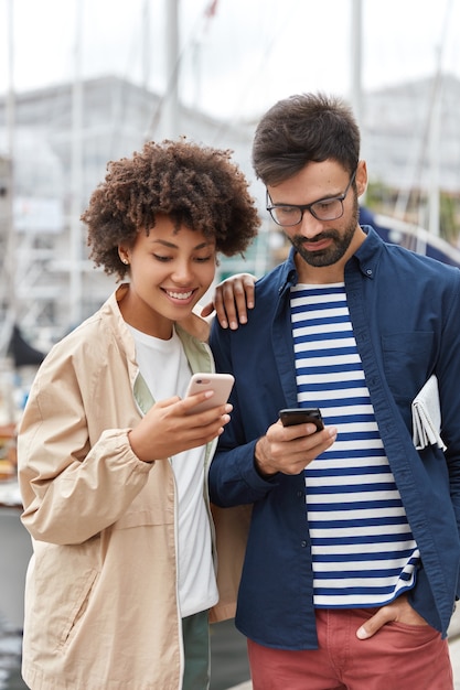 Outdoor shot of friendly interracial young woman and man dressed casually