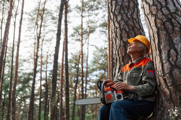 Outdoor shot of logger having rest in open air after cutting trees