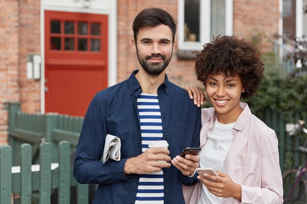 Outdoor shot of lovely couple stand closely to each other against brick building background