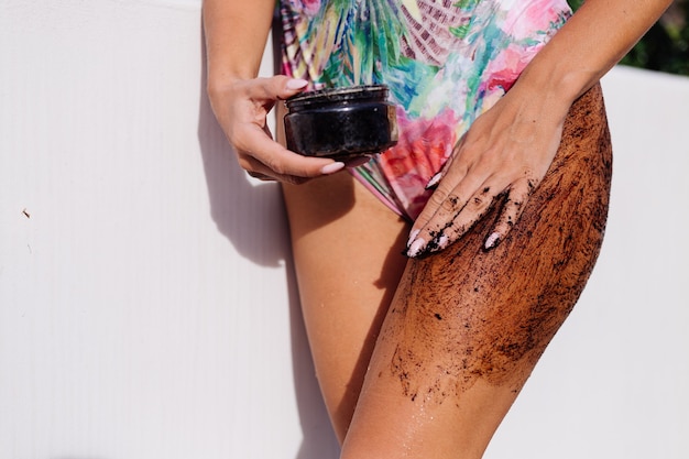 Outdoor shot of woman with coffee body scrub.