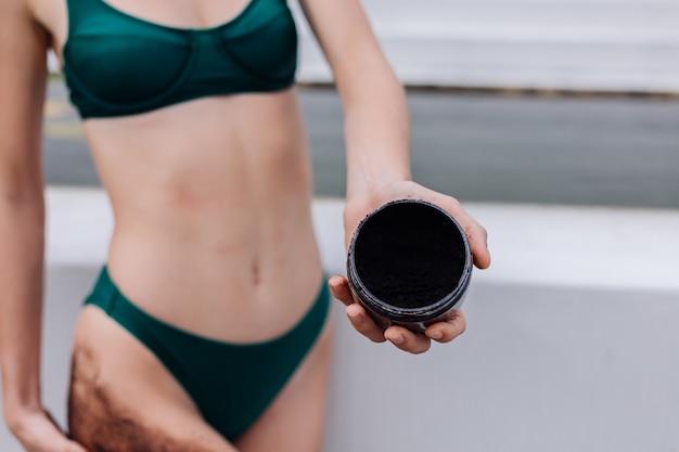 Outdoor shot of woman with coffee body scrub.