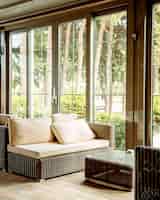 Foto gratuita divano per esterni con cuscini beige e tavolino davanti alla finestra del ristorante