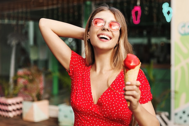 アイスクリームを食べる幸せな女性の屋外通りの肖像画