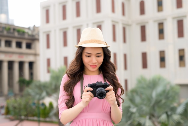 사진 작가의 카메라 여행 사진과 함께 아시아의 도시에서 즐거운 시간을 보내는 예쁜 젊은 여성의 야외 여름 웃는 라이프 스타일 초상화