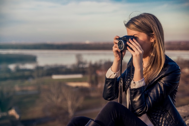 Outdoor summer smiling lifestyle portrait of pretty young woman having fun in the city in Europe in evening with camera travel photo of photographer Making pictures