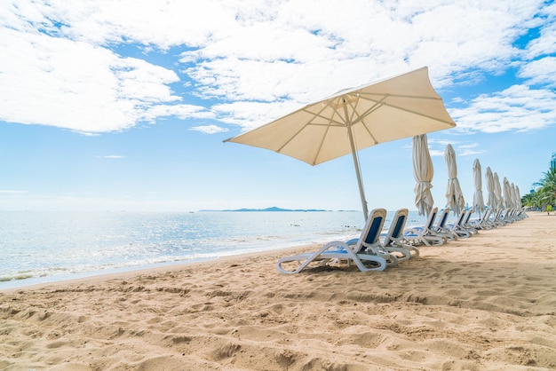 Открытый с зонтиком и стулом на прекрасном тропическом пляже и на море