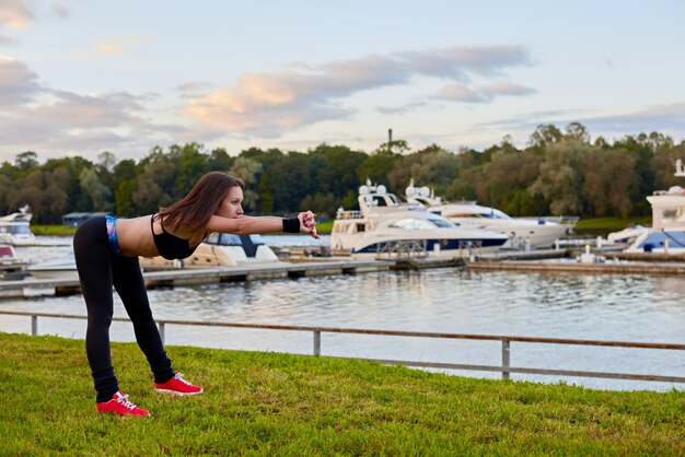 Outdoor workout on beach in evening time. Close up portrait of athletic woman, who making sport exercises for healthy life.