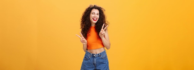 Бесплатное фото Общительная дружелюбно выглядящая привлекательная молодая женщина с кудрявой стрижкой в укороченном топе и шортах