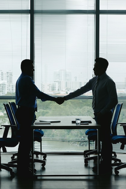 Outlines of two business people shaking hands to celebrate the win-win deal