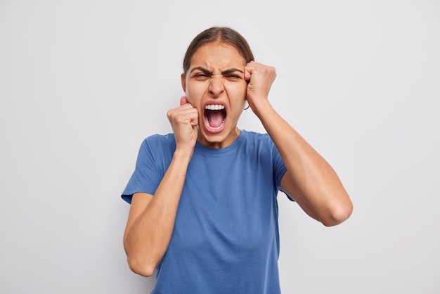 Outraged brunette European woman overreacts on something very bad looks with grief and disappointed as lost someone importan screams from disappointement keeps mouth widely opened frowns face