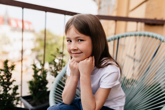 無料写真 外のバルコニーに座っている素敵なかわいい女の子の肖像画を間近します。