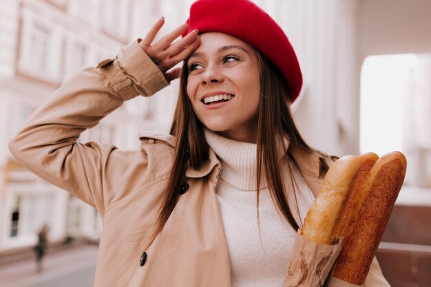 赤いベレー帽を身に着けている長い薄茶色の髪を持つ若い魅力的なフランス人女性の外の肖像画