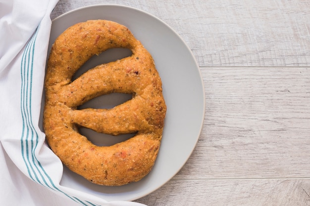 Oval shape baked bread on plate over wooden backdrop