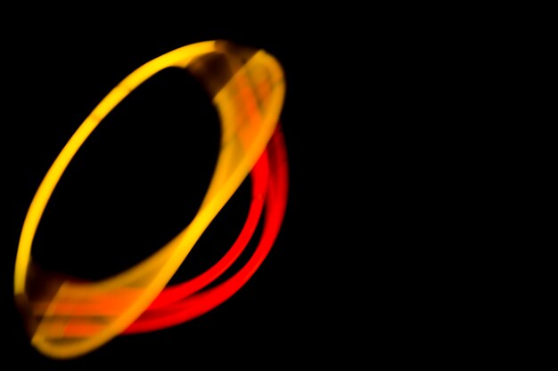 Oval shape made with neon yellow and red lights on black background