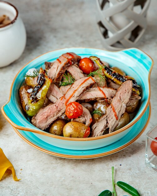 Oven-baked meat and potatoes with tomatoes and peppers