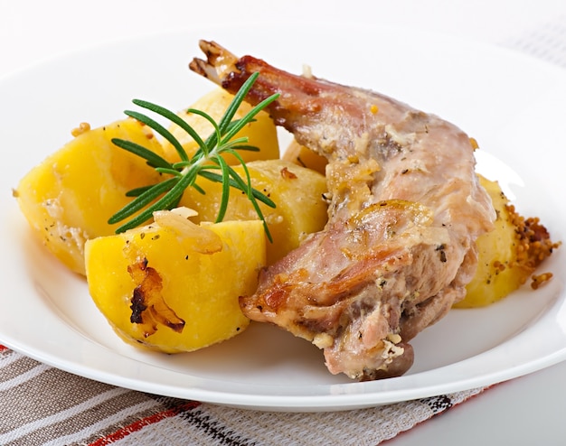 Free photo oven baked rabbit legs with potatoes and rosemary