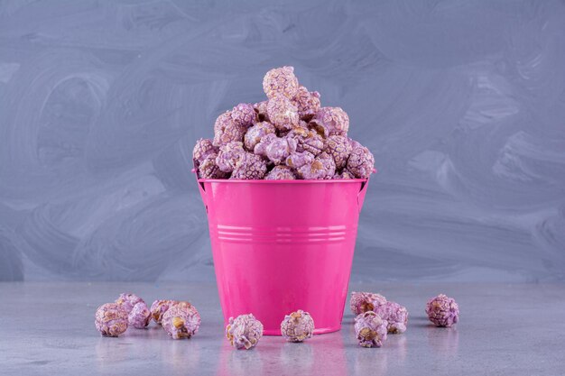 Overfilled bucket with flavored popcorn fallen out on marble background. High quality photo