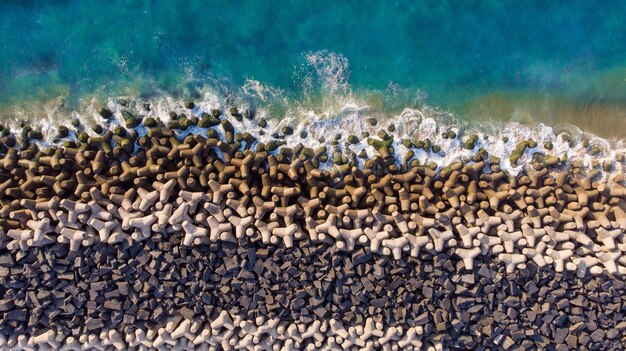 Overhead aerial shot of a wavy blue sea against the rocks