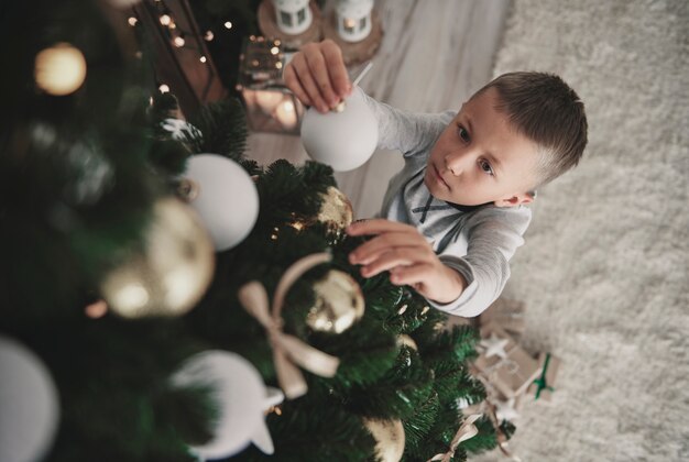 Overhead of boy in pajamas preparing a holiday tree