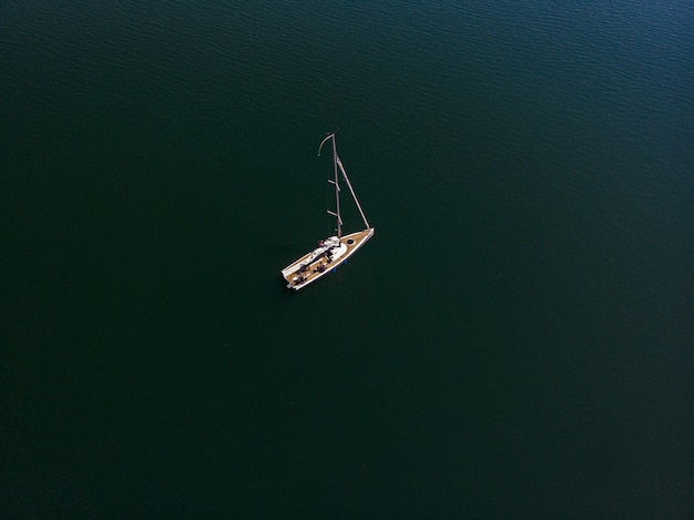Overhead drone photography of a sailing boat in a beautiful lake on a sunny day