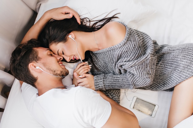 Overhead portrait of brunette man lying in bed with womanfriend