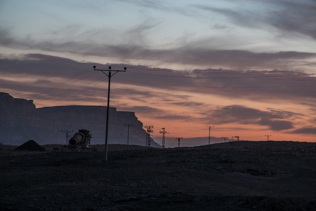 Overhead power lines in the valley under the cloudy sunset sky