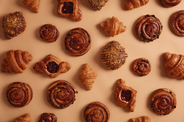 Overhead shot of appetizing delicious sweet confectionery products containing much sugar which can cause obesity and chronical diseases. Various croissants, buns and swirls to choose in bakers shop