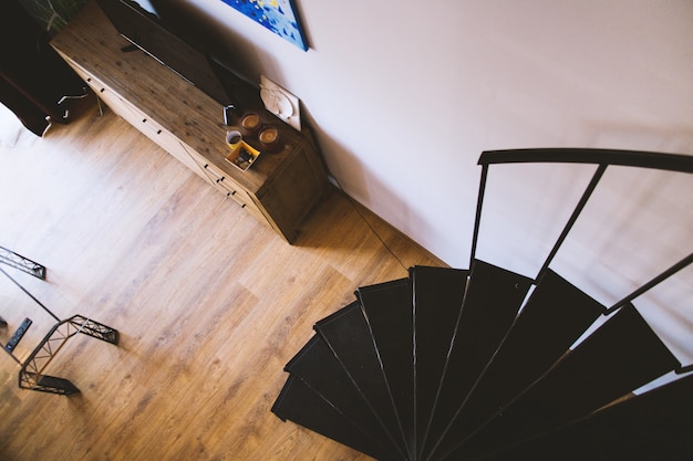 Overhead shot of black spiral stairs near a drawer with a TV on top