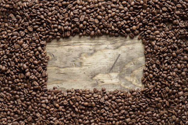 背景やテキストの書き込みに最適な木製の表面上のコーヒー豆フレームのオーバーヘッドショット