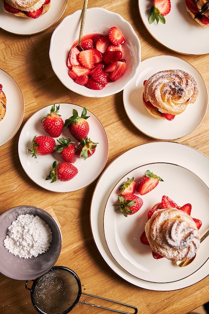 木製のテーブルにイチゴとチョコレートとおいしいシュークリームのオーバーヘッドショット