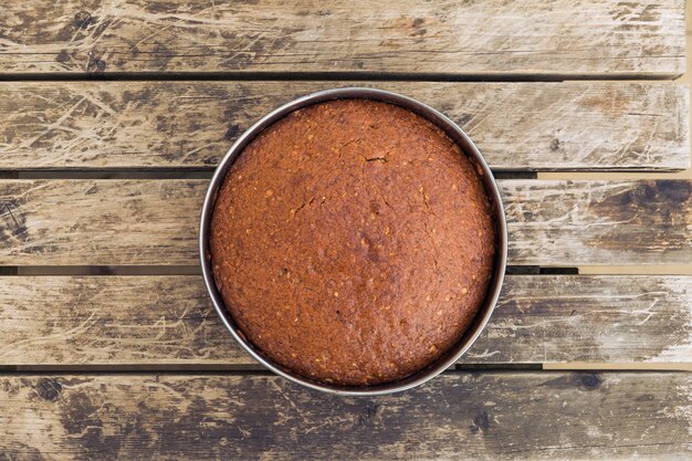 Overhead shot of a deliciously baked cake in a round mold on a wooden surface