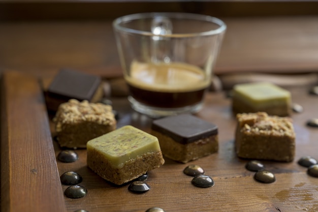 Free photo overhead shot of different types of square-shaped sweets with tea on a wooden tray