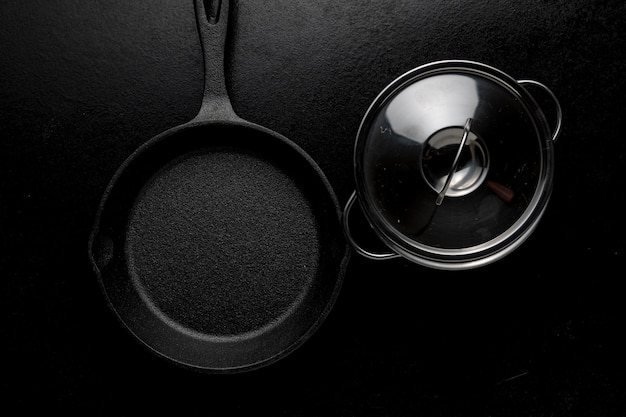 Overhead shot of a frying pan and its lid on a black table