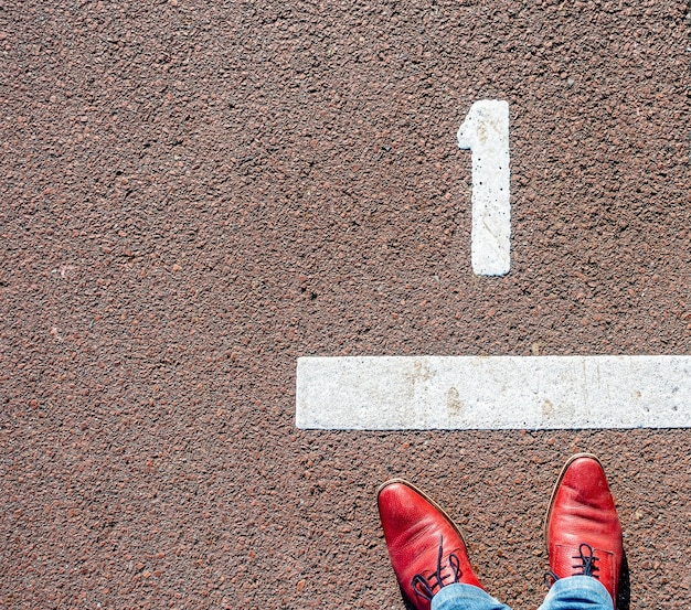 Overhead shot of a man in red shoes standing in front of a number "1" line