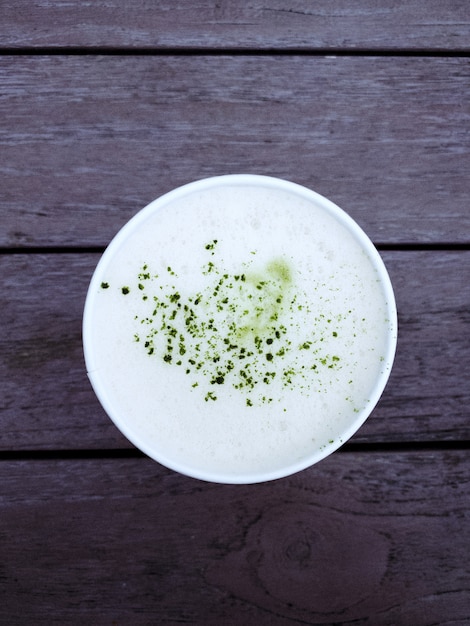 Foto gratuita colpo sopraelevato di un latte del tè verde di matcha su una tavola di legno rustica