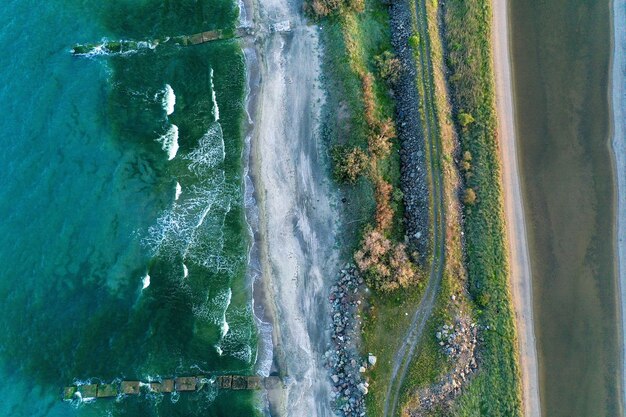 Overhead shot of a narrow shore in the middle of the sea with pathway and greenery on it