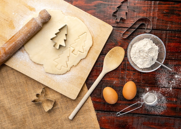 Scatto dall'alto di pasta cruda e formine per biscotti di natale sul tavolo della cucina rustica