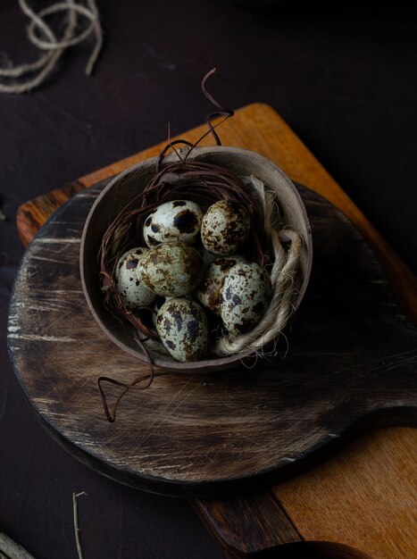 Overhead shot of speckled quail eggs with jute twine in a rustic bowl on a wooden board