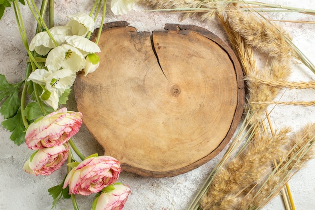 Overhead shot of wooden platter and emmers and flowers around it on marble