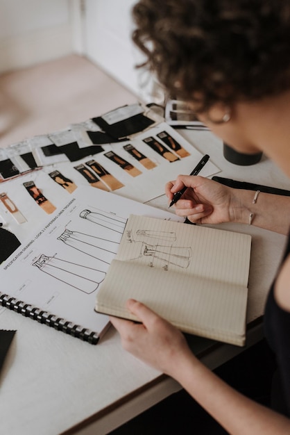 Free photo overhead shot of  young businesswoman and fashion designer reviewing her clothes design sketches