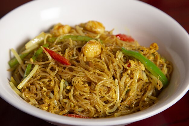 Overhead top view of a bowl of curry noodles on a wooden surface