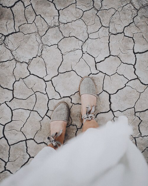 Overhead vertical shot of a female's feet on a cracked ground