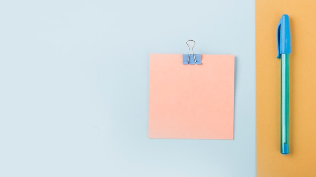 Overhead view of adhesive note and pen on multi colored cardboard paper