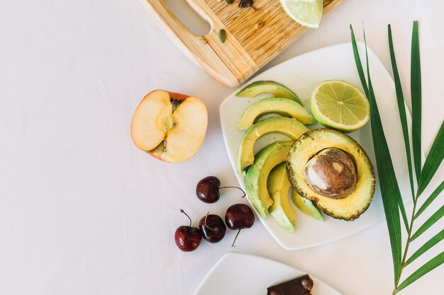 An overhead view of avocado; apple and cherries on white background