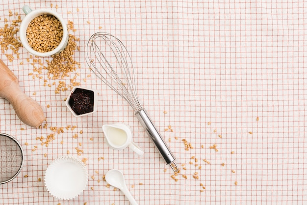 Foto gratuita vista ambientale degli ingredienti e degli utensili di cottura sopra tessuto a quadretti bianco