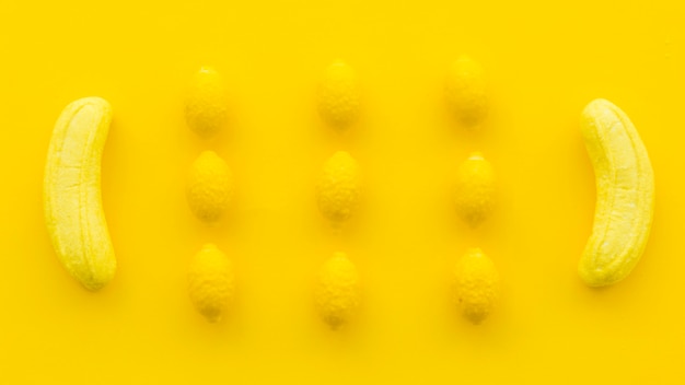 Overhead view of banana and lemon candies on yellow backdrop