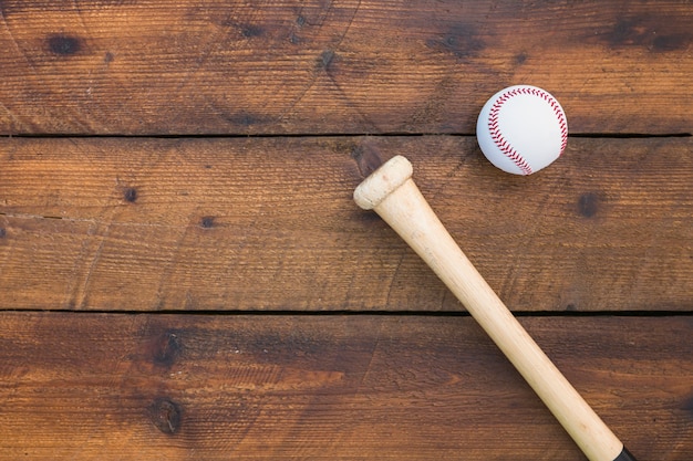 An overhead view of baseball bat and ball on wooden table