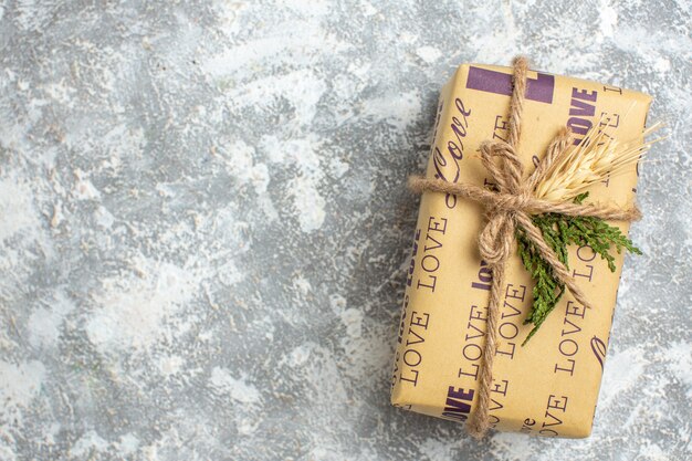 Overhead view of beautiful Christmas packed gift with love inscription on the left side on ice surface