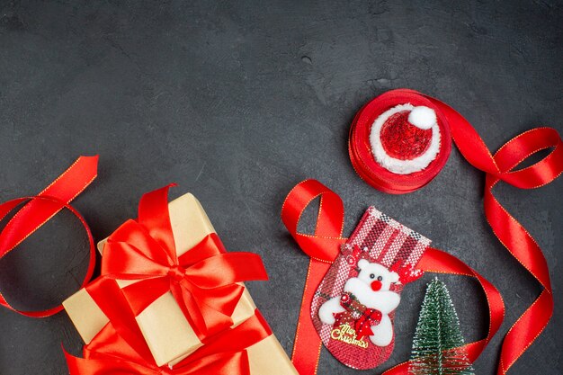 Overhead view of beautiful gifts and xsmas sock christmas tree santa claus hat on dark background